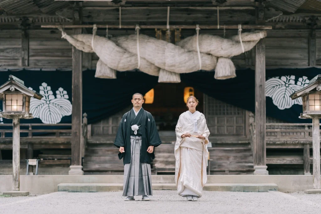 神社の境内で和装に身を包む新郎新婦