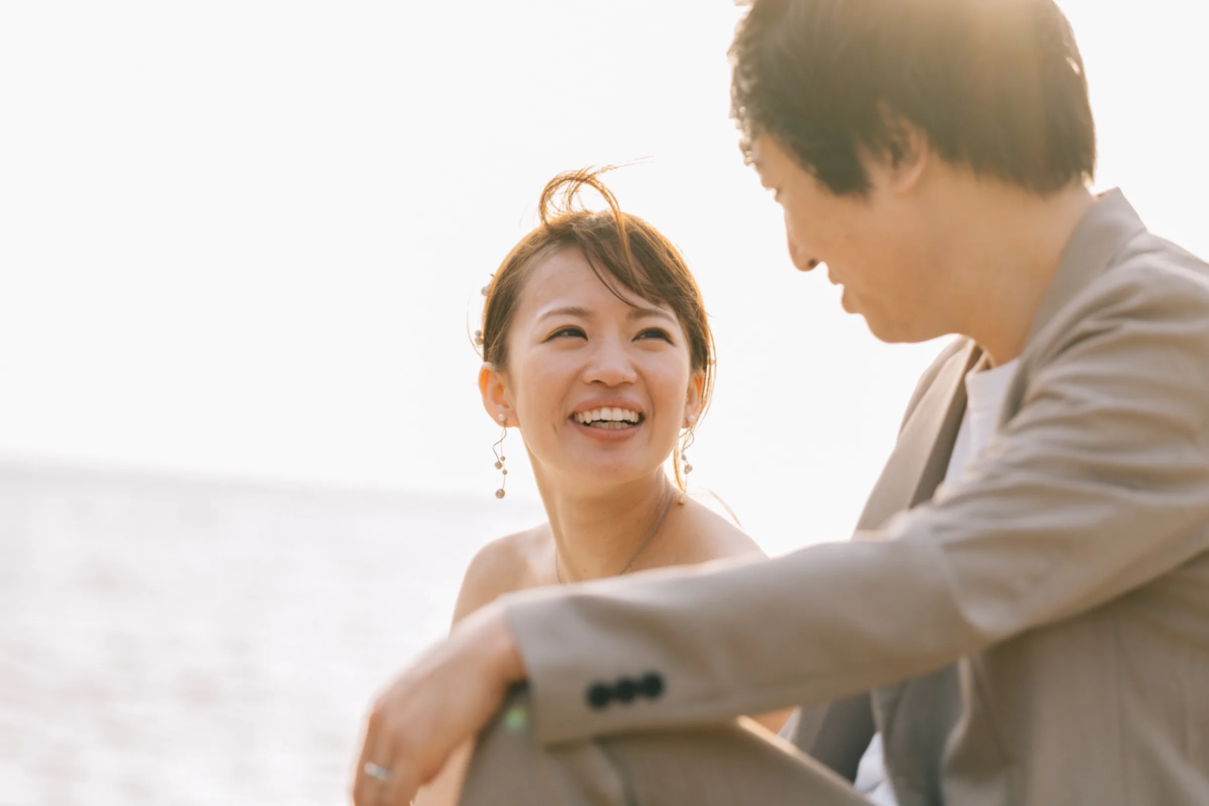 夕暮れの海辺で手をつなぐ新郎新婦