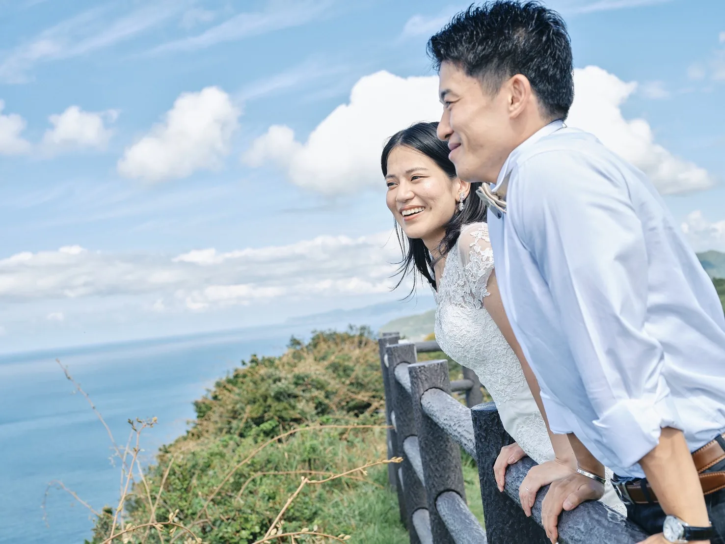 展望の柵にもたれ、海を見て笑う新郎新婦