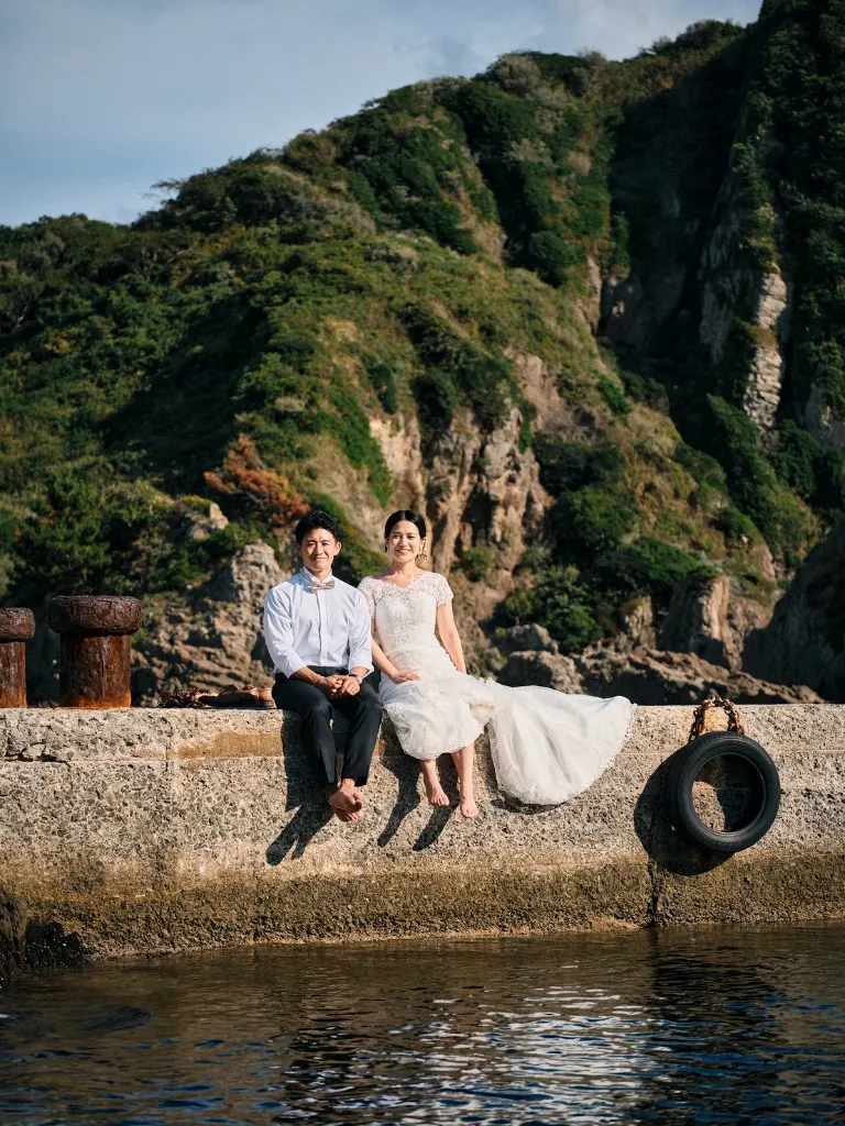 国賀海岸の突堤に腰かけ、裸足で座る新郎新婦