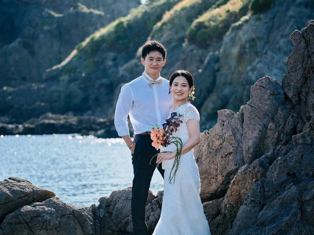 国賀海岸の岩場でブーケを持つ新郎新婦